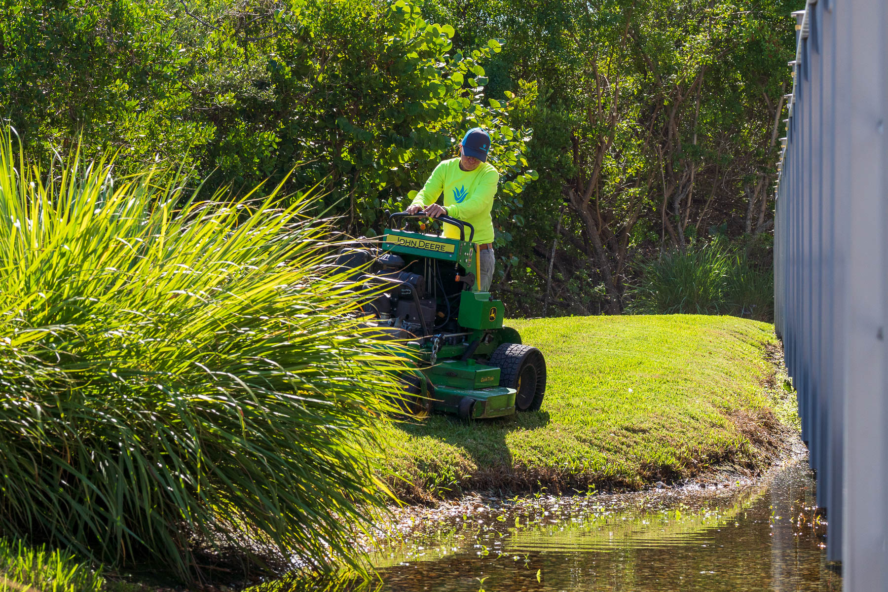 Landscape maintenance crew mowing along fence