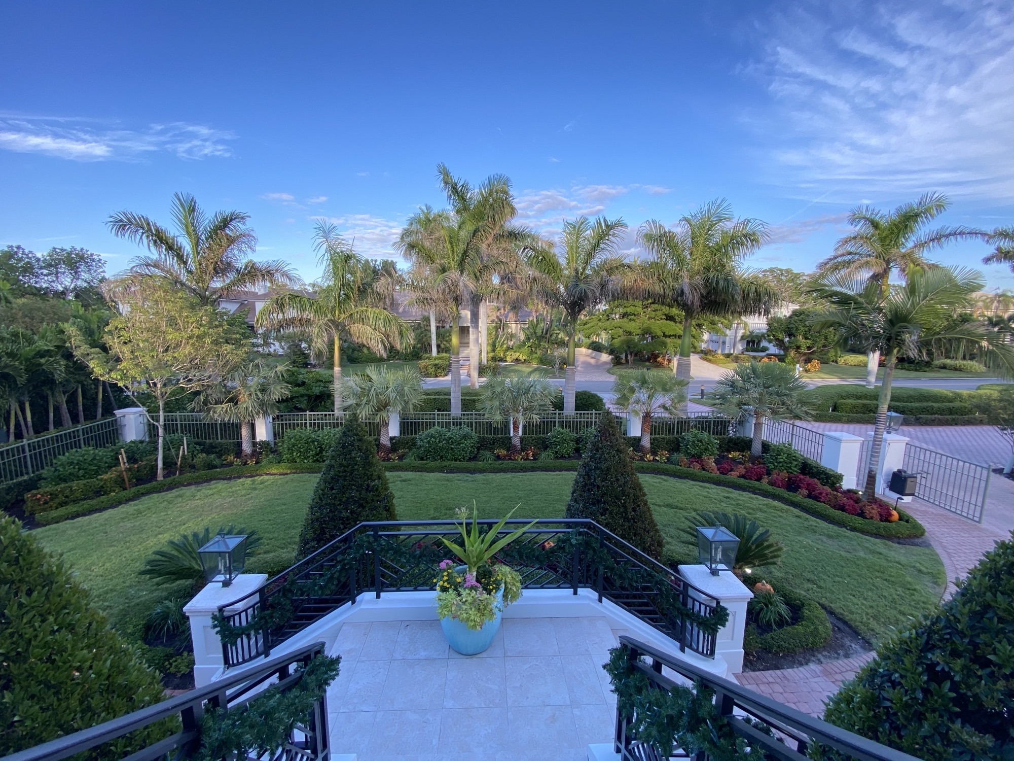 front yard with beautiful flower beds along iron fence 